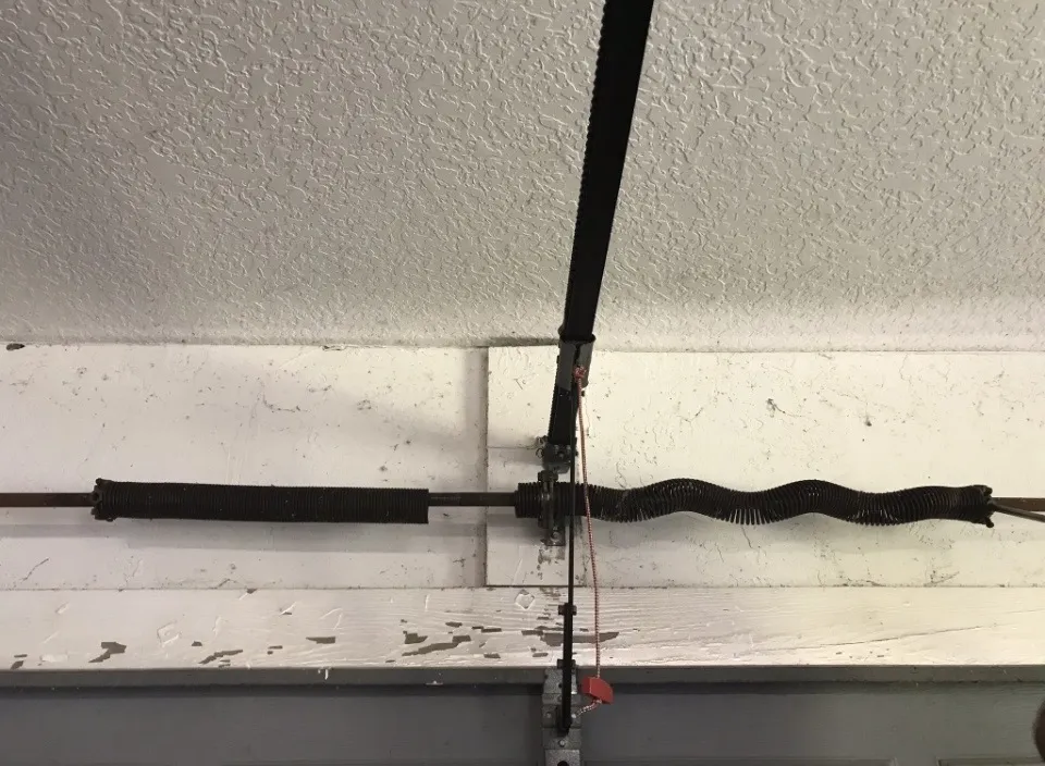 Broken wavy garage door torsion spring and intact drive belt.
