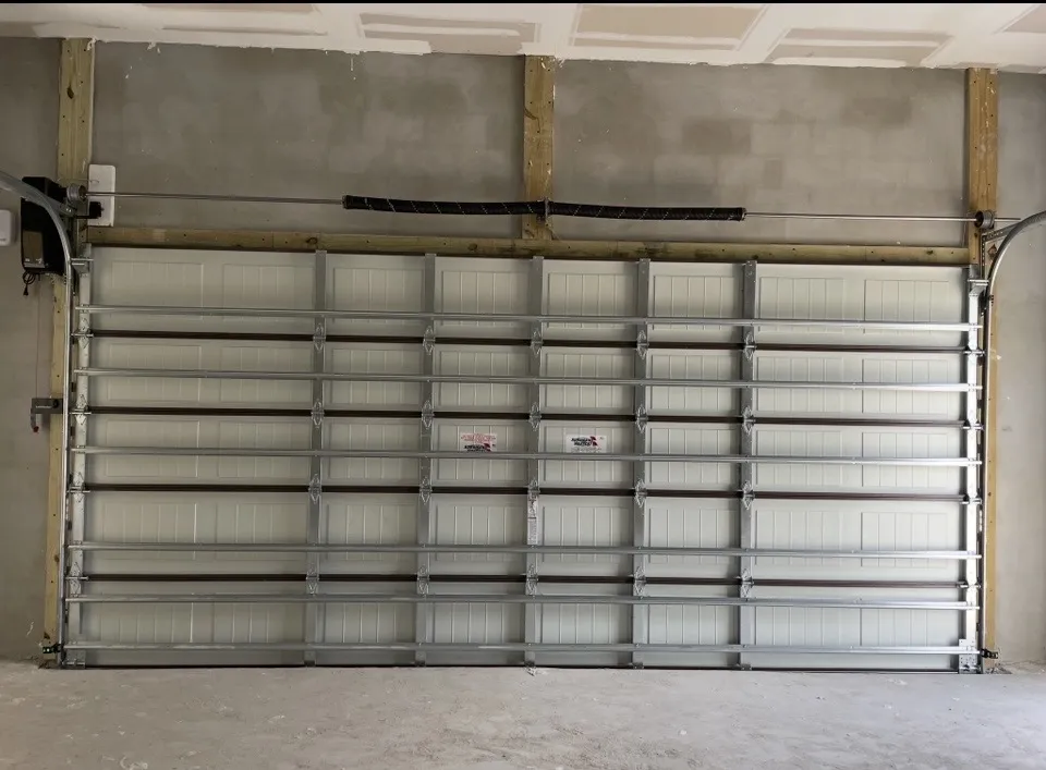 Industrial garage door in a concrete setting, partially open with tracks visible.