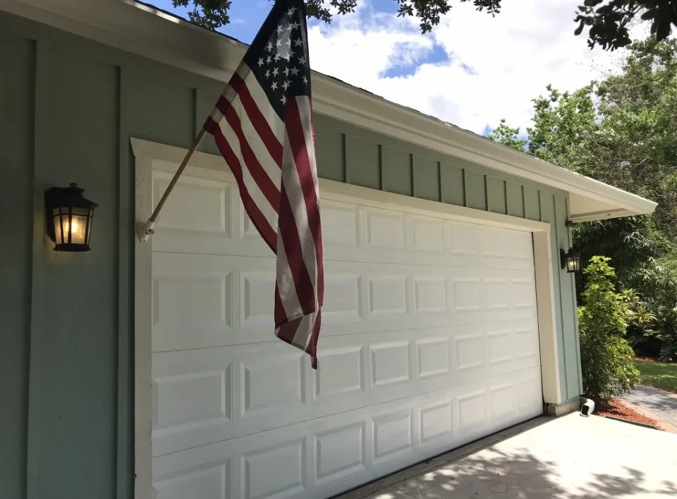 American flag hanging next to a white garage door on a house