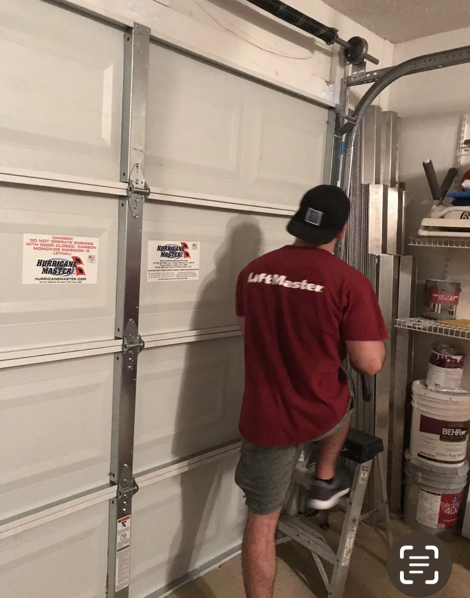 Technician conducting safety checks on garage door equipment with PPE